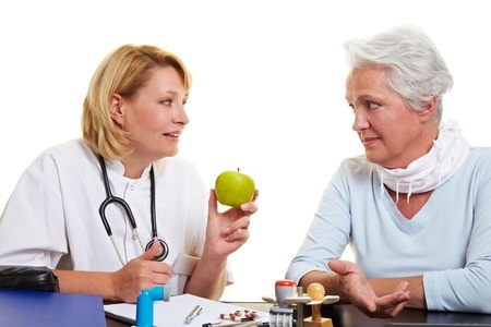 10582313 - doctor recommending a green apple to senior woman