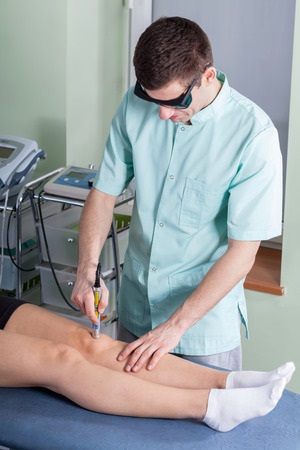 Doctor performing knee test in consulting room