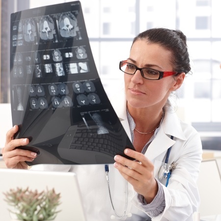 28345386 - portrait of female brunette doctor with x-ray image in hand, wearing glasses, stethoscope and lab coat,